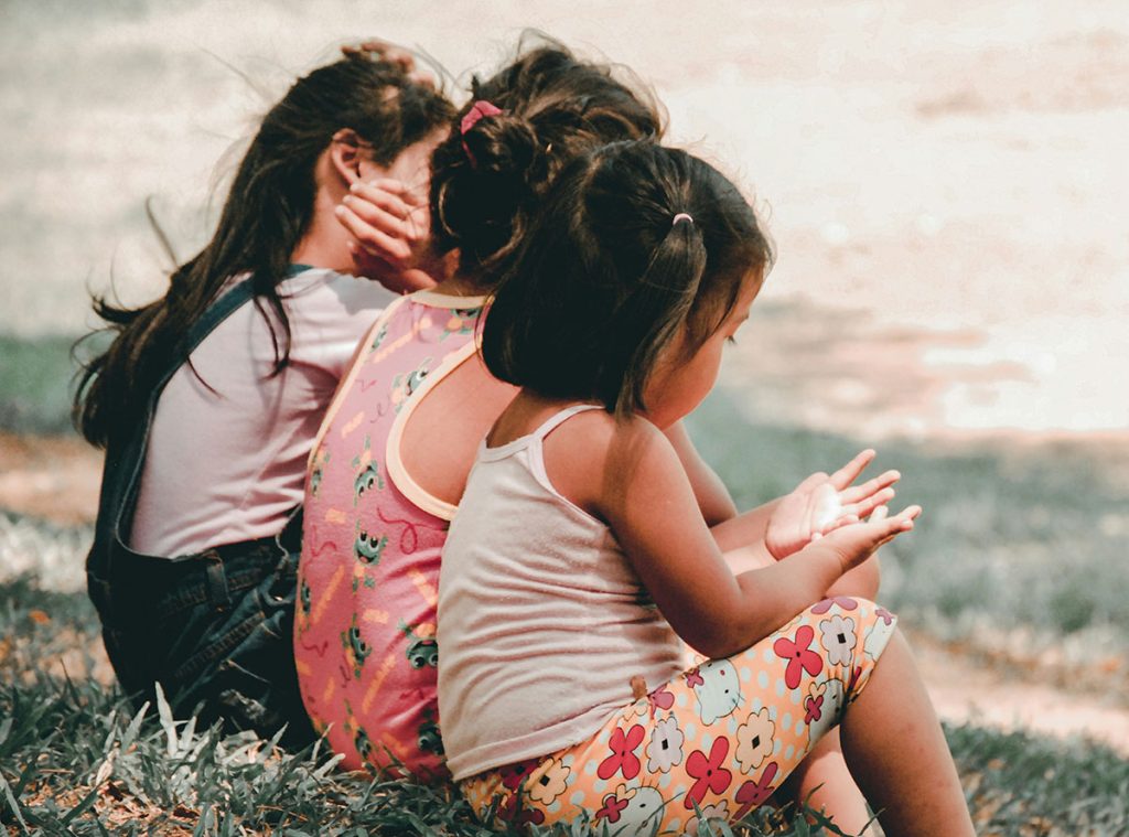 We offer legal advice for child protection matters. Three children sit on a hill looking away from the camera.
