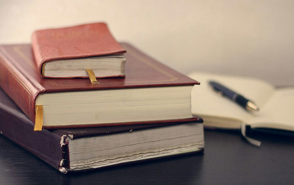 A stack of legal books with a notepad and pen. Niigaan Miikaans offers a variety of legal services.